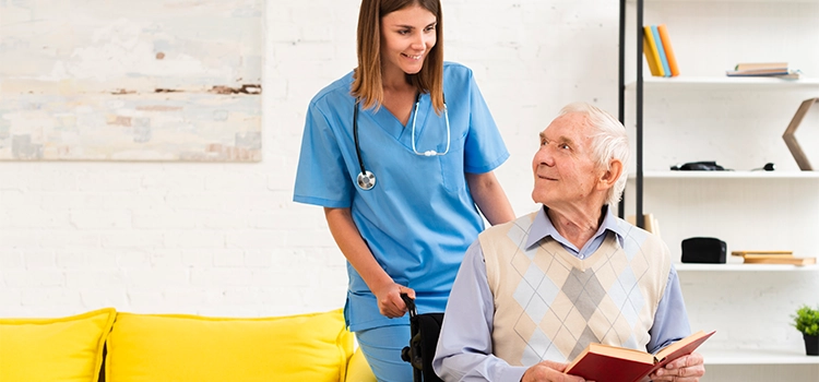 An elderly guy in a wheelchair conversing merrily with a care worker.