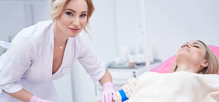 Female healthcare professional securing catheter in patient’s vein with adhesive tape.